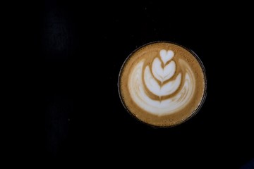 Hot coffee cafe latte in a glass cup in a cafe with black background