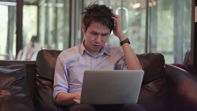 man under a lot of stress using laptop computer in cafe