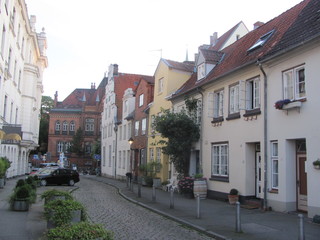 A street in a small cozy European (German) town: low houses with tiled roofs, flowers