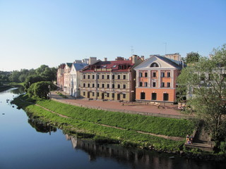 Beautiful embankment in Pskov, Russia, a row of beautiful houses and a river on a summer sunny day