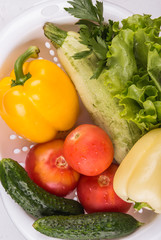 Fresh vegetables in a colander bowl on a white background