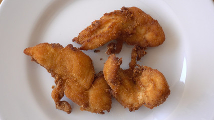 Pieces of meat appetizing chicken in breaded. The chicken on the plate rotates against the background of the wooden table. Top view, close-up.