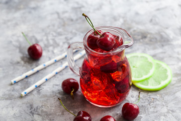 Cherry lemonade, iced summer cocktail, in a glass jar, gray background Copy space
