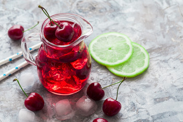 Cherry lemonade, iced summer cocktail, in a glass jar, gray background Copy space