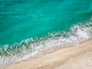 Above view of the turquoise mediterranean sea hitting the beach.