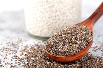 Healthy Chia seeds in a wooden spoon and chia pudding in glass jar on the table close-up.