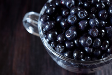 Close-up of bilberries in a glass cup against the dark background