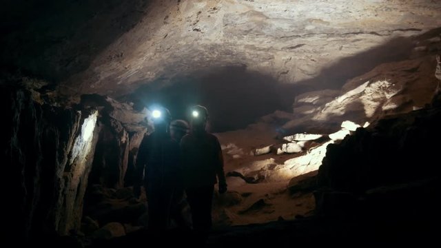 Children in helmets with lanterns comes into a dark cave