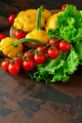 organic yellow patissons with cherry tomatoes and salad on a wooden table. a new harvest of vegetables from the garden, vegan food, a diet food. selective focus and copy space