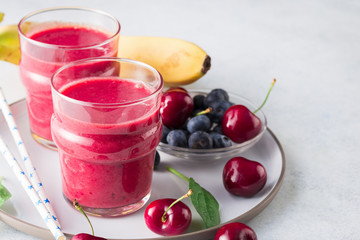 Cherry spinach smoothies decorated fresh cherries on blue stone background. Delicious diet healthy drink. 