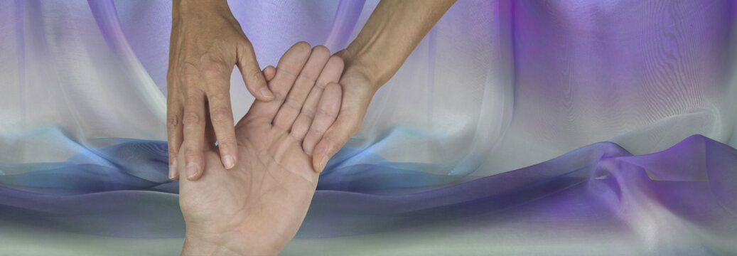 Palmistry website header on purple material background      Palmist holding man's hand reading and assessing his lines on a wide purple chiffon background with copy space
