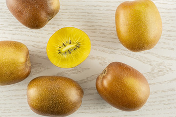 Group of five whole one half of fresh golden brown kiwi fruit sungold variety flatlay on grey wood