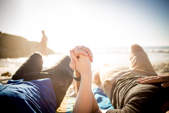 Close up image of a gay male couple holding hands on the beach in cape town south africa