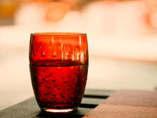 Transparent red glass with water on table.