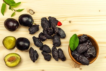Prune, dried plums fruits on rustic wooden background. Dry plums in a wooden bowl. Healthy fruit.