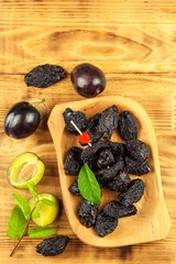 Prune, dried plums fruits on rustic wooden background. Dry plums in a wooden bowl. Healthy fruit.