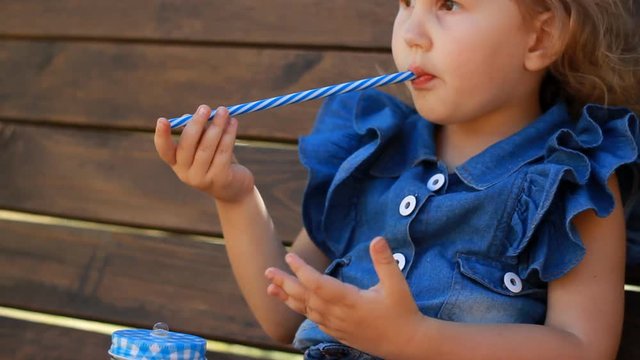 Child girl drinks smoothies in the park on a sunny day. Close up
