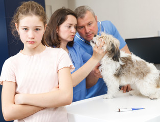 Worried girl with puppy visiting veterinarian clinic