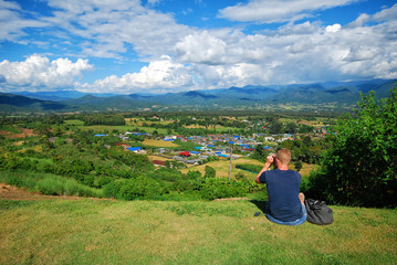 Fototapeta na wymiar a man sit on the yard and seeing the view scenary landscape of Pai district in Mae Hong sorn, Thailand