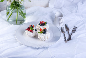 Delicate white meringues with fresh berries on the plate. Dessert Pavlova. White background. Wedding cake.