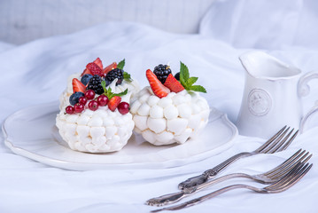 Delicate white meringues with fresh berries on the plate. White background. Wedding cake.