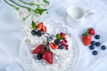 Delicate white meringues with fresh berries on the plate on white background. Dessert Pavlova. Wedding cake.