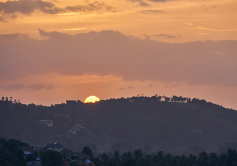 The village in the valley against the background of the sun setting over mountains             
