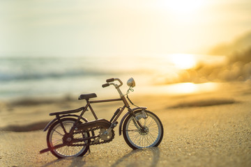 bicycle transport toy on sand sea beach in the evening sunset sky , with yellow light beam