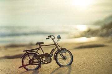 Fototapeta na wymiar bicycle transport toy on sand sea beach in the evening sunset sky