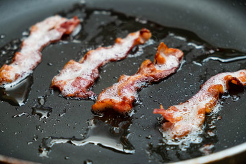 slices of fresh fried bacon in a pan for breakfast