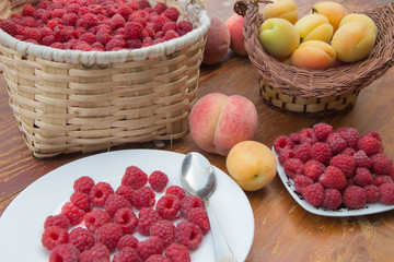 Fresh Raspberry basket, peaches and Apricot in a wicker basket on wooden table
