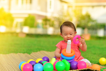 Cute Asian baby playing with toys in playground
