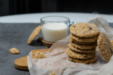 Oatmeal cookies and milk on a wooden board and gray background