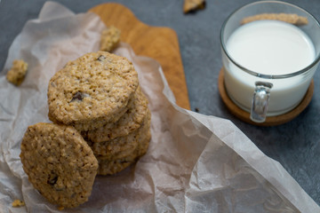 Oatmeal cookies and milk on a wooden board and gray background