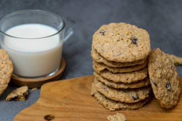 Oatmeal cookies and milk on a wooden board and gray background