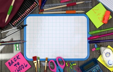 Back to school concept: school and office items with a white board on a wooden background.