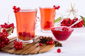 Vitamin healthy viburnum berry warm drink in glass cups with fresh raw viburnum berries  on a white kitchen table.