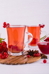 Vitamin healthy viburnum berry warm drink in glass cups with fresh raw viburnum berries  on a white kitchen table.