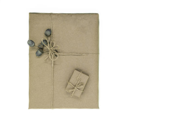 Composition of gift boxes wrapped in beige paper and bundled with ribbons. Decorated with young oak acorns in white background surface
