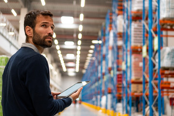 Manager in warehouse holding digital tablet