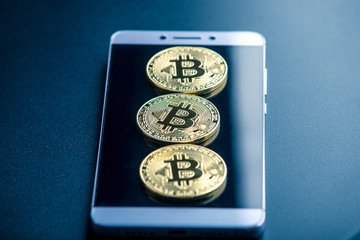 Physical bitcoin coin on the phone screen. Concept of cryptocurrency and blockchain