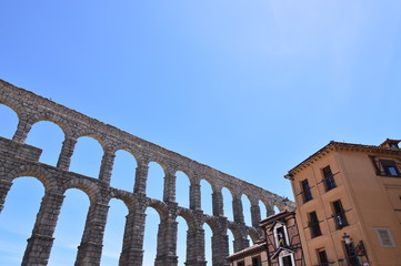 Fototapeta premium Oblique Photo Of The Aqueduct With Person Making A Photo From A Balcony Of A Nearby Bar In Segovia. Architecture, Travel, History. June 18, 2018. Segovia Castilla Leon Spain.