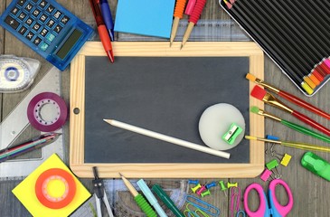 Back to school concept: office and school supplies with a blackboard on a wooden background.