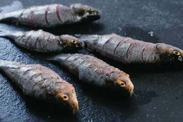 Fresh cleaned carp sprinkle with salt on the black table.