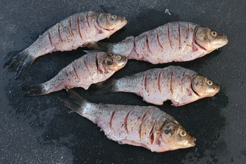 Carp in spices on a black table close-up. Top view.