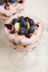 Two glass cup, with granola oat meals, with dried fruits, blueberries and yogurt. Isolated on...