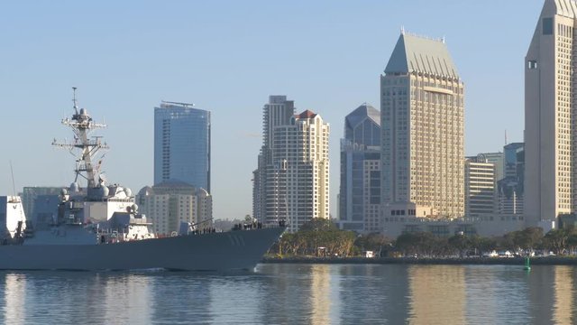Warship sails against the background of San Diego's downtown in the morning at dawn.