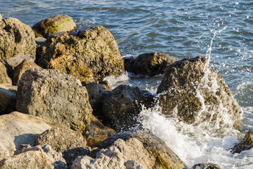 Sea waves are fighting against the big rocks on the shore.