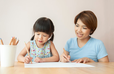 Happy Asian Mother and daughter drawing together.