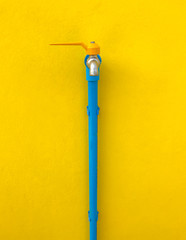 faucet with blue water pipe on yellow wall.